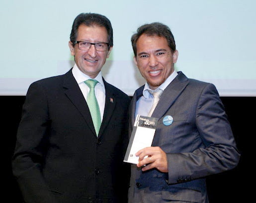 Alessandro Santiago (à dir.) recebe o prêmio de Wilson Moherdaui, diretor editorial da Plano Editorial