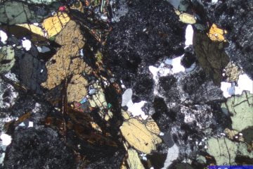 Imagem de amostra de rocha preparada (cortada, colada em vidro e desbastada) para atingir 0,03 mm de espessura e permitir a passagem de luz