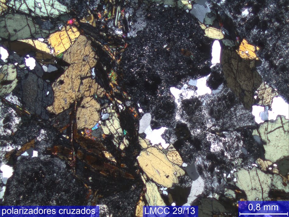 Imagem de amostra de rocha preparada (cortada, colada em vidro e desbastada) para atingir 0,03 mm de espessura e permitir a passagem de luz