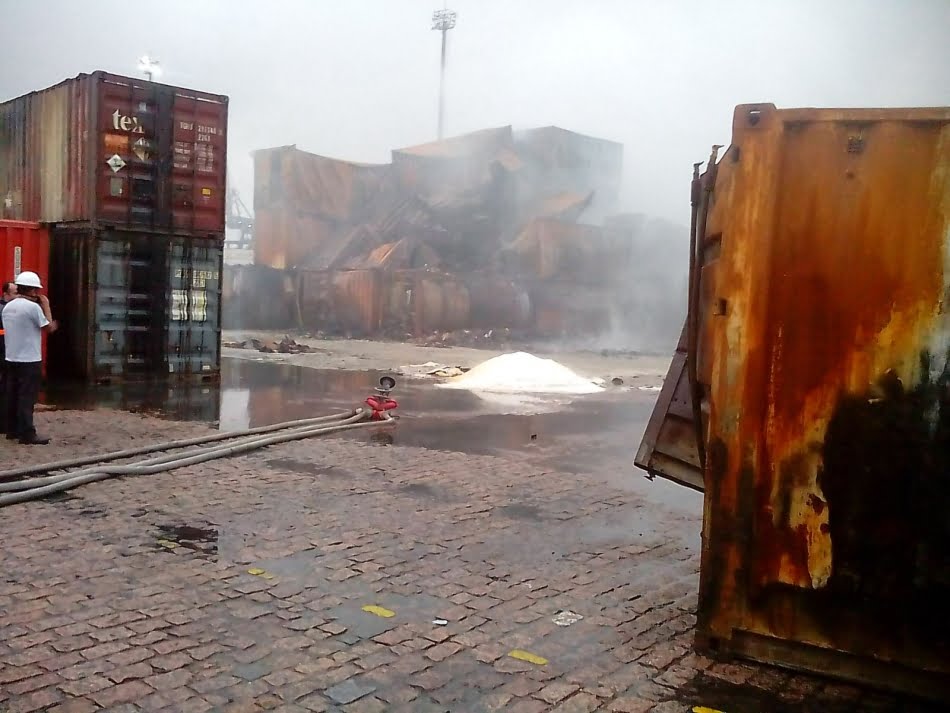 Material usado no experimento em pequena escala para verificar riscos e vantagens do método proposto pela equipe que incluía os técnicos do IPT - ao fundo, pode-se observar a névoa que estava sendo emitida nos contêineres ainda em chamas