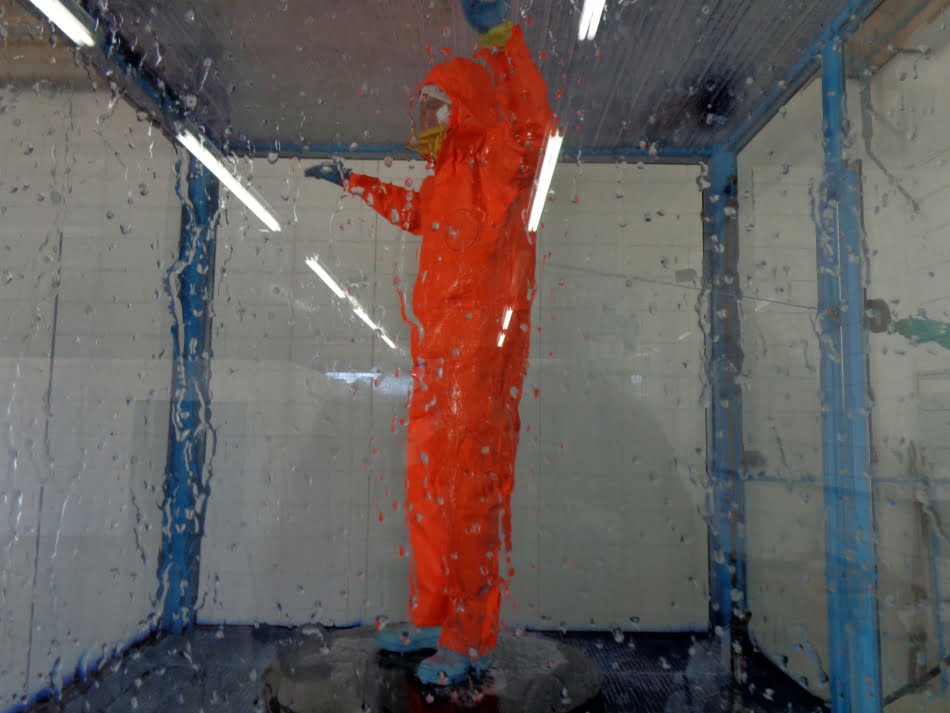 Macacão é submetido a ensaio de exposição a agente de risco para avaliar resistência à penetração de líquidos por jato